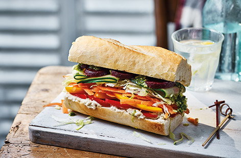 Put some colour into lunch with this vibrant veg-packed baguette that's bursting with fresh ingredients. Creamy houmous and punchy pesto add a boost of flavour while the layered veg create different textures and fun rainbow effect for a healthy lunch.